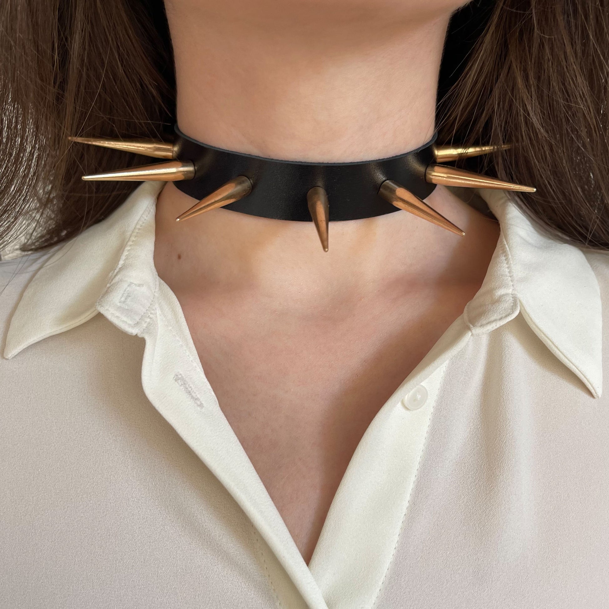 Leather spiked collar worn on the neck, front view, with long gold-colored cone spikes across the collar