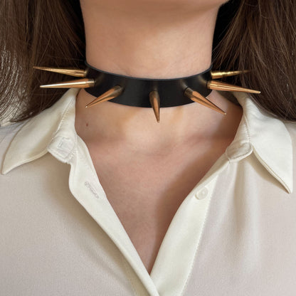 Leather spiked collar worn on the neck, front view, with long gold-colored cone spikes across the collar