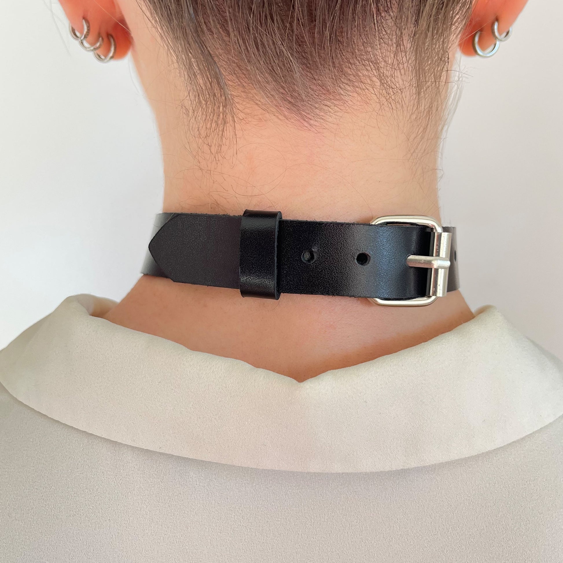 Back view of black leather choker with silver buckle and keeper loop, styled on neck with blouse collar