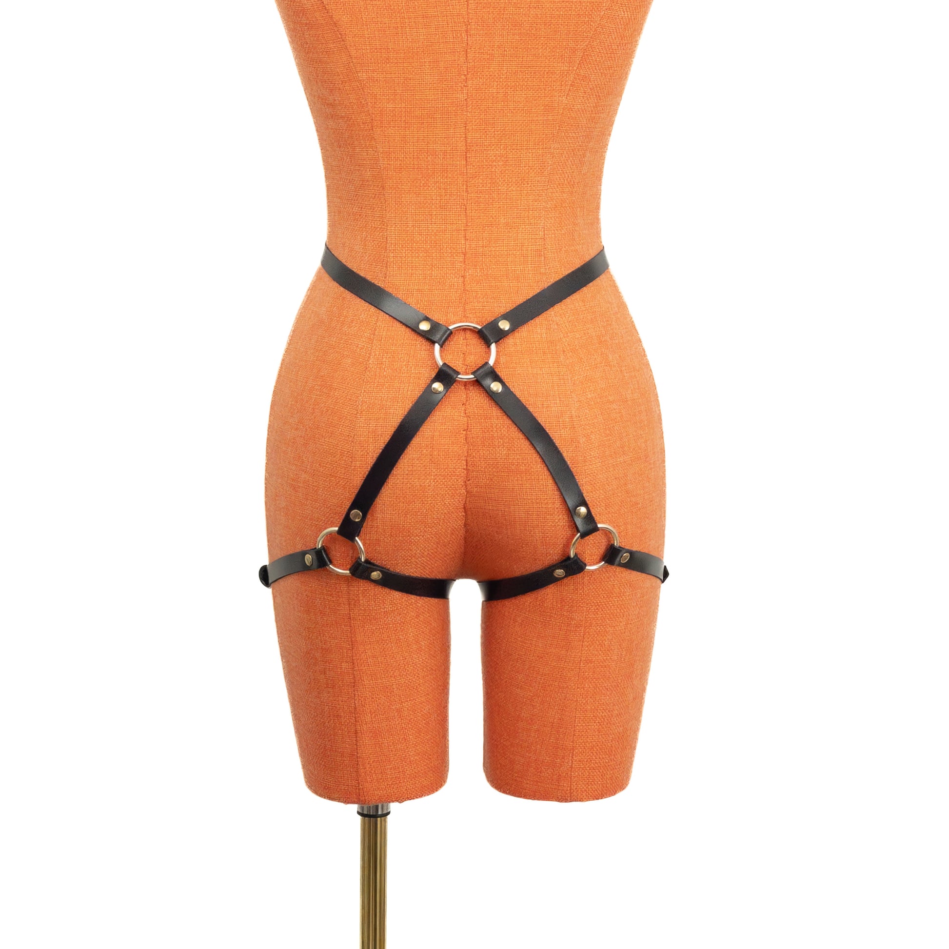 Slim leather butt garter made of black genuine leather with gold hardware, rear view on mannequin, 5/8 inch (15 mm) waist strap connected to central back ring with two slim straps running diagonally over the buttocks to adjustable thigh bands.