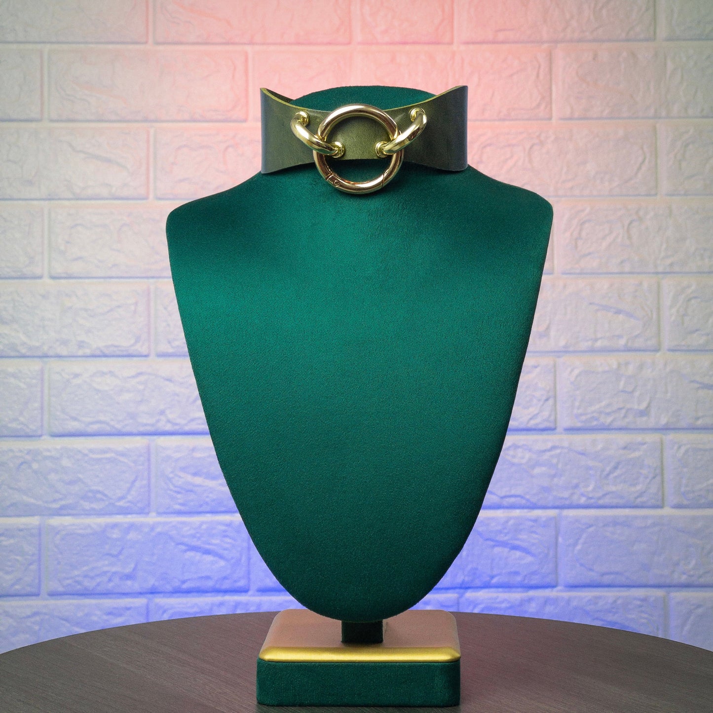 Green mannequin head with a green collar and gold hardware on a textured white background