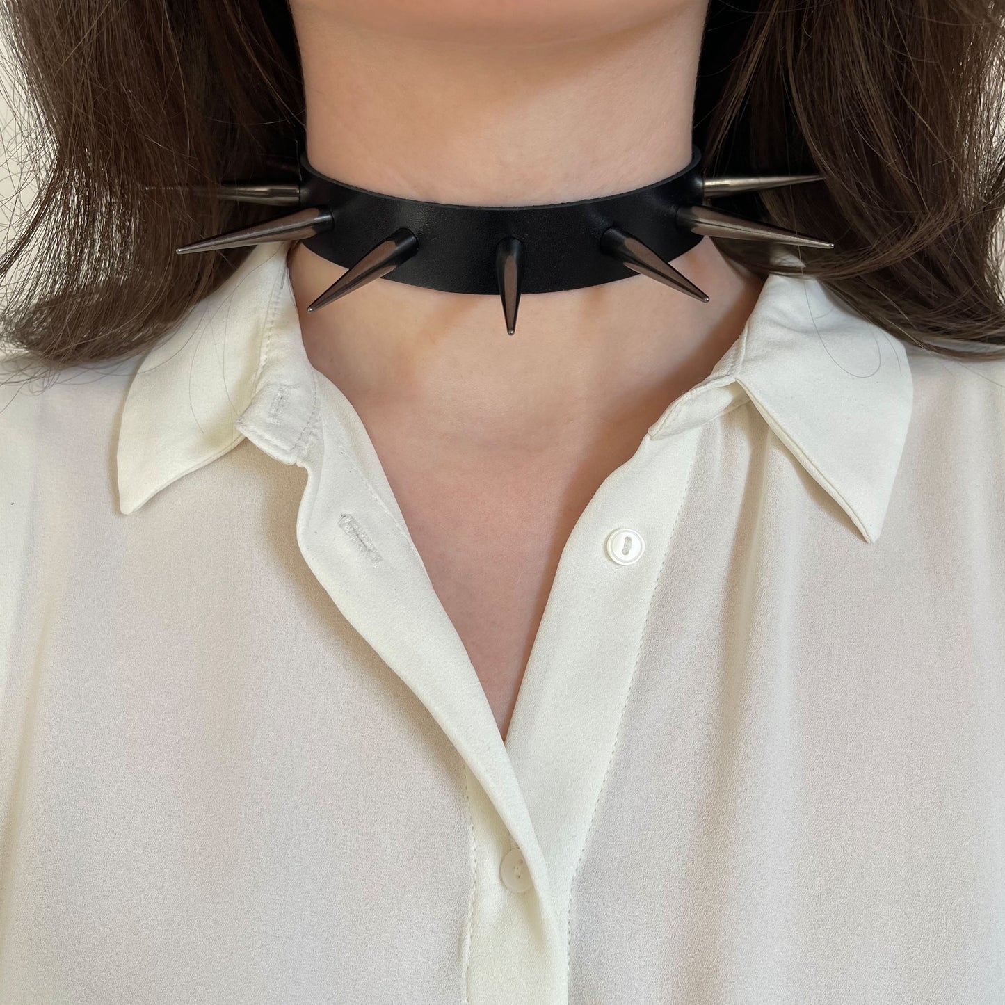 Leather spiked collar worn on the neck, front view, with long cone spikes in dark nickel color