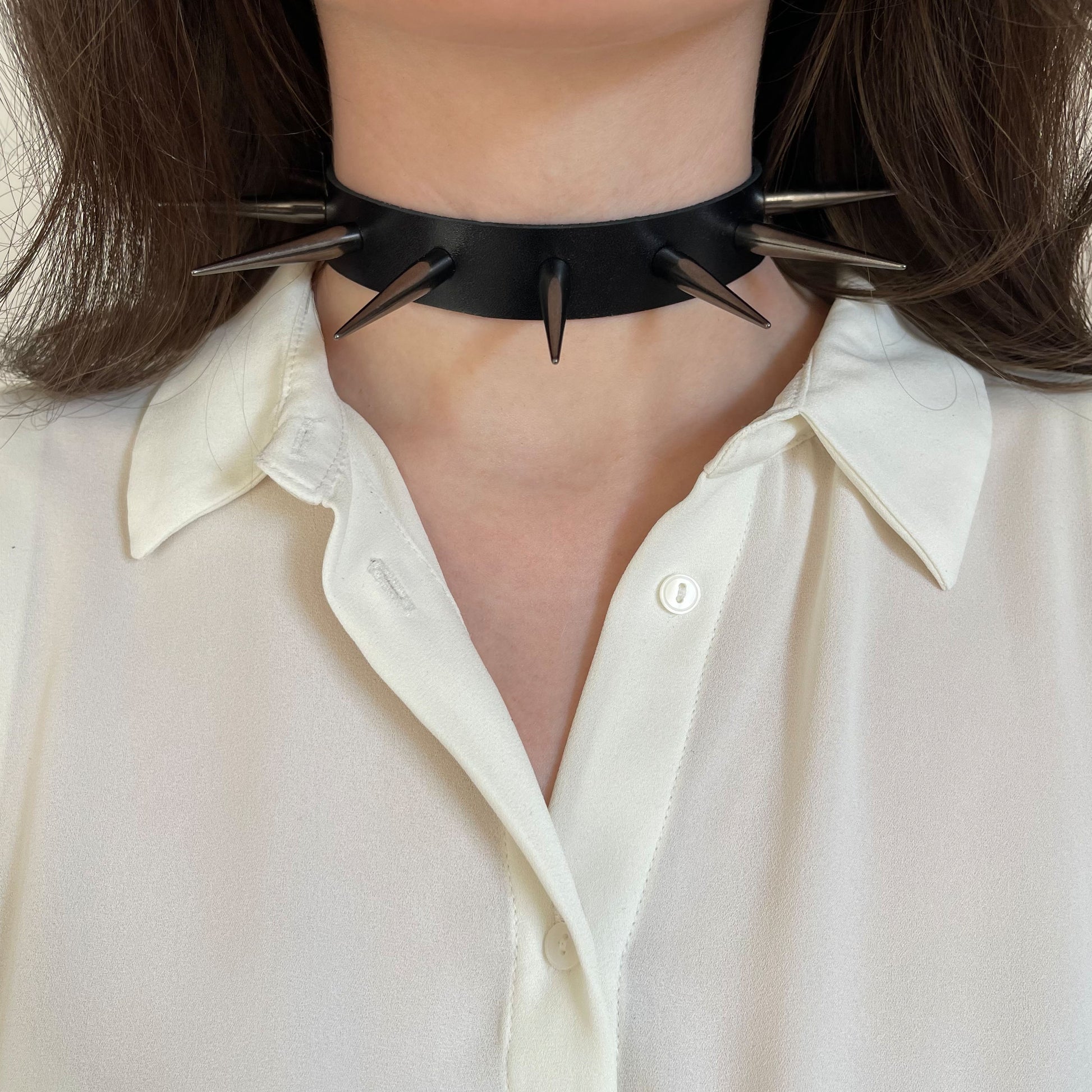 Leather spiked collar worn on the neck, front view, with long cone spikes in dark nickel color
