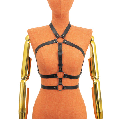 Front view of a black leather open chest harness displayed on a mannequin, showing the neck ring with five straps, central adjustable strap, triangular chest openings, and two underbust straps connected by round rings; dark nickel hardware; leather thickness 1.4–1.8 mm.