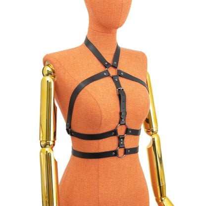 Three-quarter side view of a black leather open chest harness on a mannequin, showing how straps wrap from the neck ring toward the underbust ring and continue around the torso, forming a double underbust line; dark nickel buckles and rings visible; leather thickness 1.4–1.8 mm.