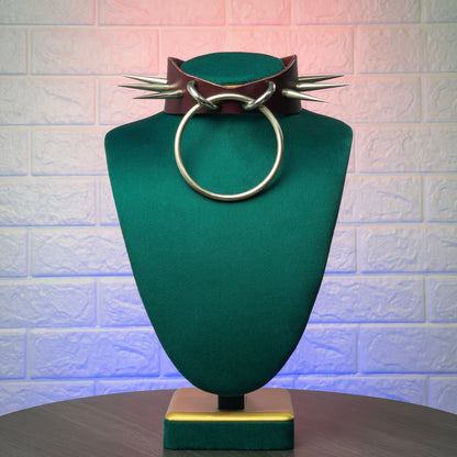 Jewelry display with a marsala leather collar and circular metal ring and spikes on a textured background