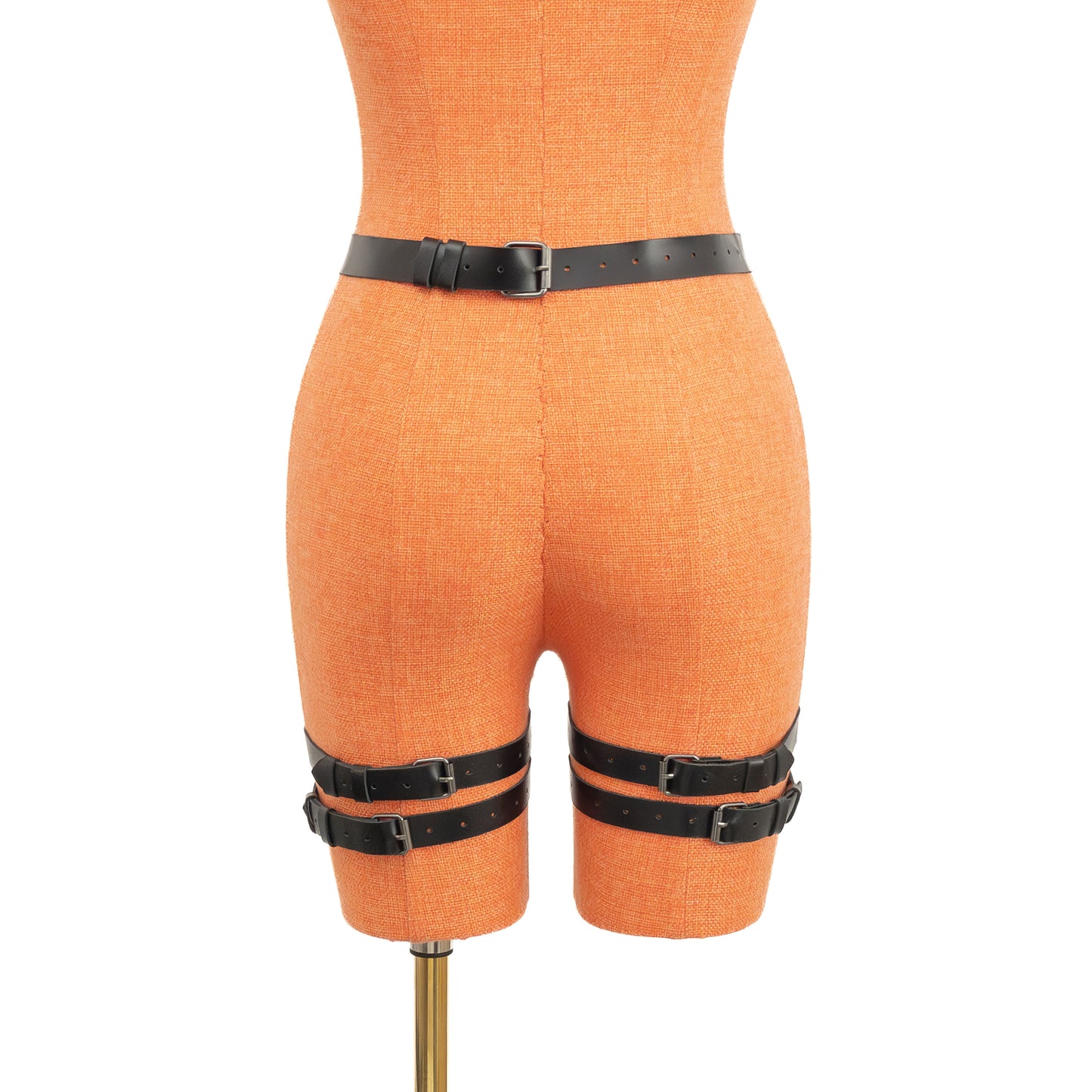Rear view of the black leather garter belt on a mannequin. The 1 inch (2.5 cm) waist strap fastens with a dark nickel buckle, and two vertical straps descend to double 3/4 inch (2 cm) thigh bands secured with matching metal buckles on the back of each leg.