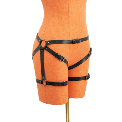 Leather thigh strap harness made of black genuine leather with dark nickel hardware, side view on mannequin, visible outer hip ring and adjustable thigh straps secured with buckles.