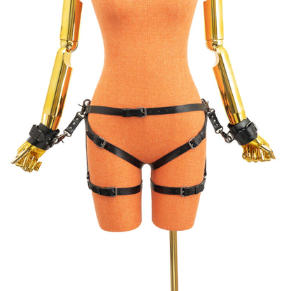Front view of an open crotch hip ring garter belt set on a mannequin in black leather, showing the waist strap with front buckle, side hip rings, straps passing through the crotch, lower leg rings, adjustable thigh straps, and wrist cuffs attached to the side rings by leather connectors with carabiners.