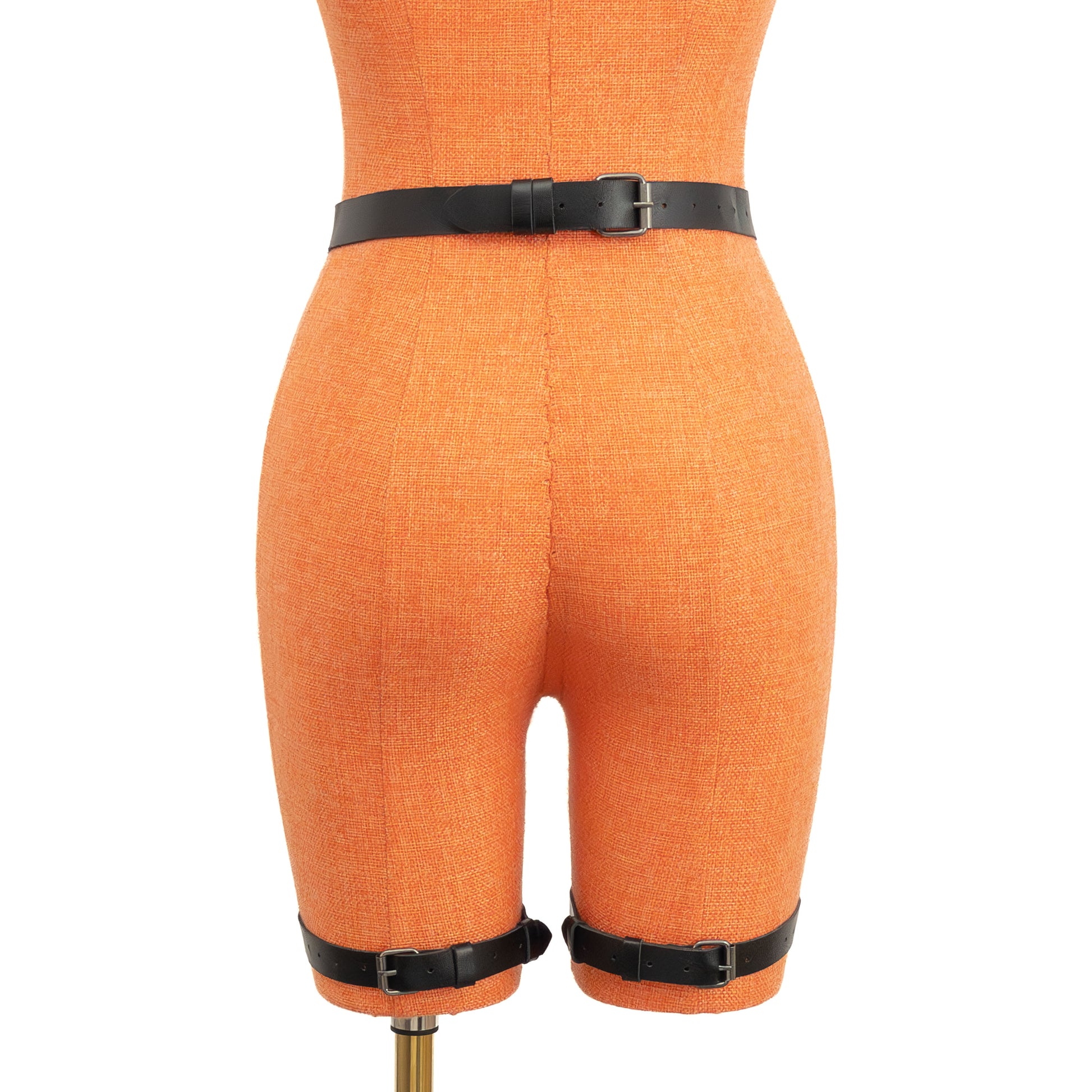 Back view of the black leather garter belt displayed on a mannequin. The 1 inch (2.5 cm) waist strap and two thigh straps are shown with dark nickel buckles and strap keepers, evenly spaced on both legs. This view focuses on rear fastening points and strap placement.