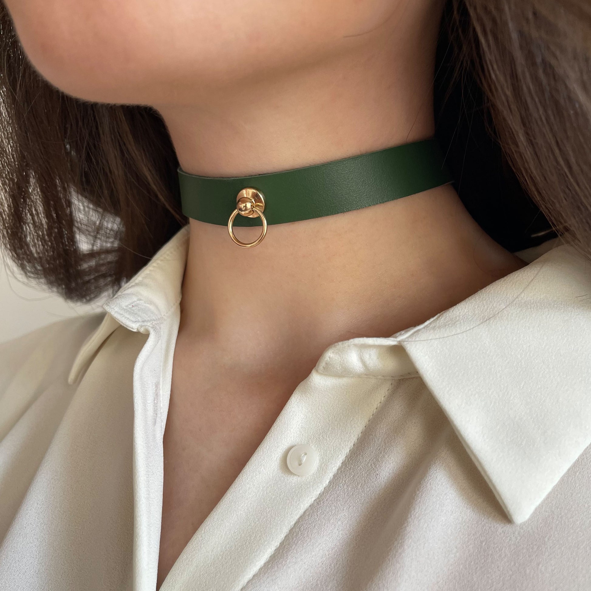 Minimalist green leather choker with a central gold ring. Width: 1.5 cm (0.59 in). Made from semi-matte genuine leather (1.4–1.8 mm thick). Pictured on a woman's neck in a white shirt from the side, showing the clean shape and refined style.