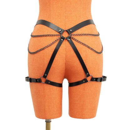 Rear view of the black leather butt garter on an orange mannequin. Chains run from front belt rings toward a central back ring positioned on the butt area, forming a double-chain pattern across the hips and butt. Thigh straps fasten with dark nickel buckles.