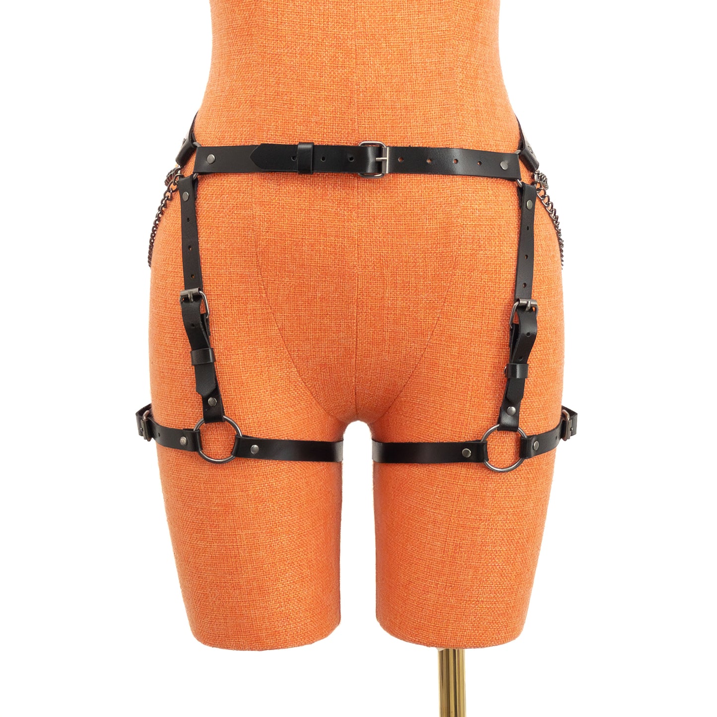 Front view of the black genuine leather butt garter displayed on an orange mannequin. A narrow waist strap with a center front buckle connects to vertical adjustable straps and horizontal thigh straps positioned evenly around both legs.