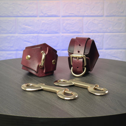 Two leather handcuffs with metal buckles on a dark surface.