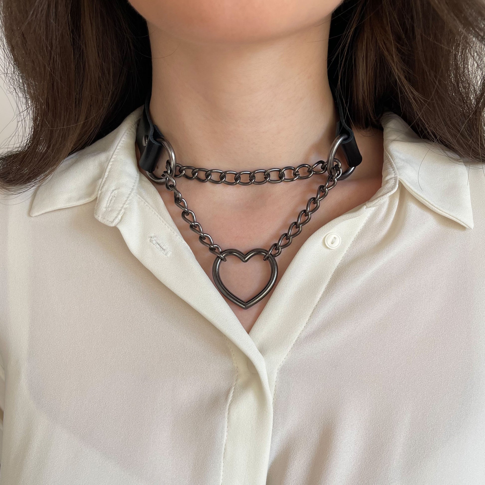 Black genuine leather choker with dark metal double chain and heart ring, tight around neck
