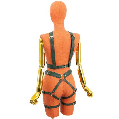Back view of a green leather wide reversible body harness set on a mannequin, showing the side with two back shoulder straps, an underbust belt, a waist belt, a central back garter ring, diagonal straps across the buttocks, lower side rings, and gold hardware.