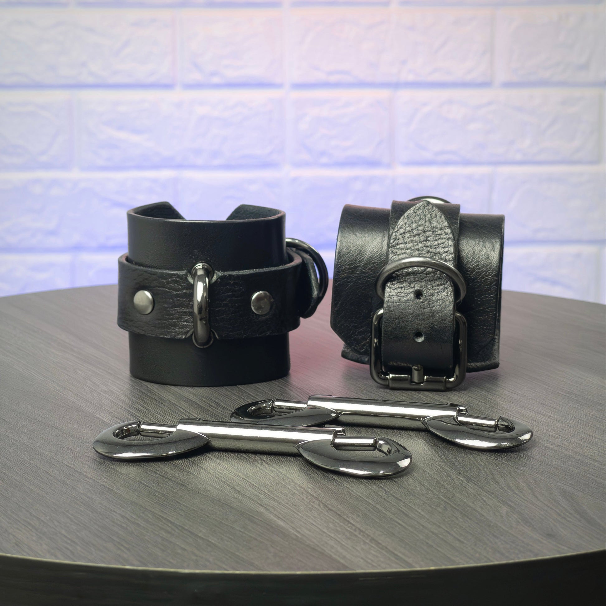 Black leather cuffs with metal buckles on a wooden surface