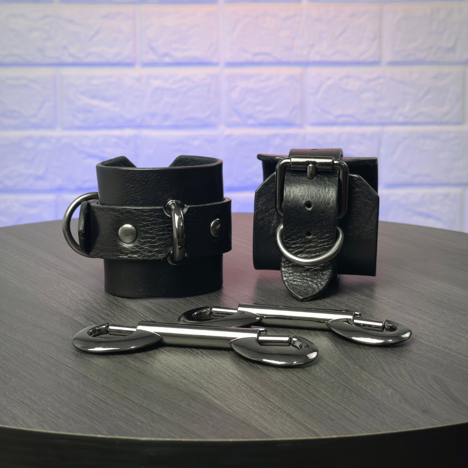 Black leather cuffs with metal hooks on a dark surface