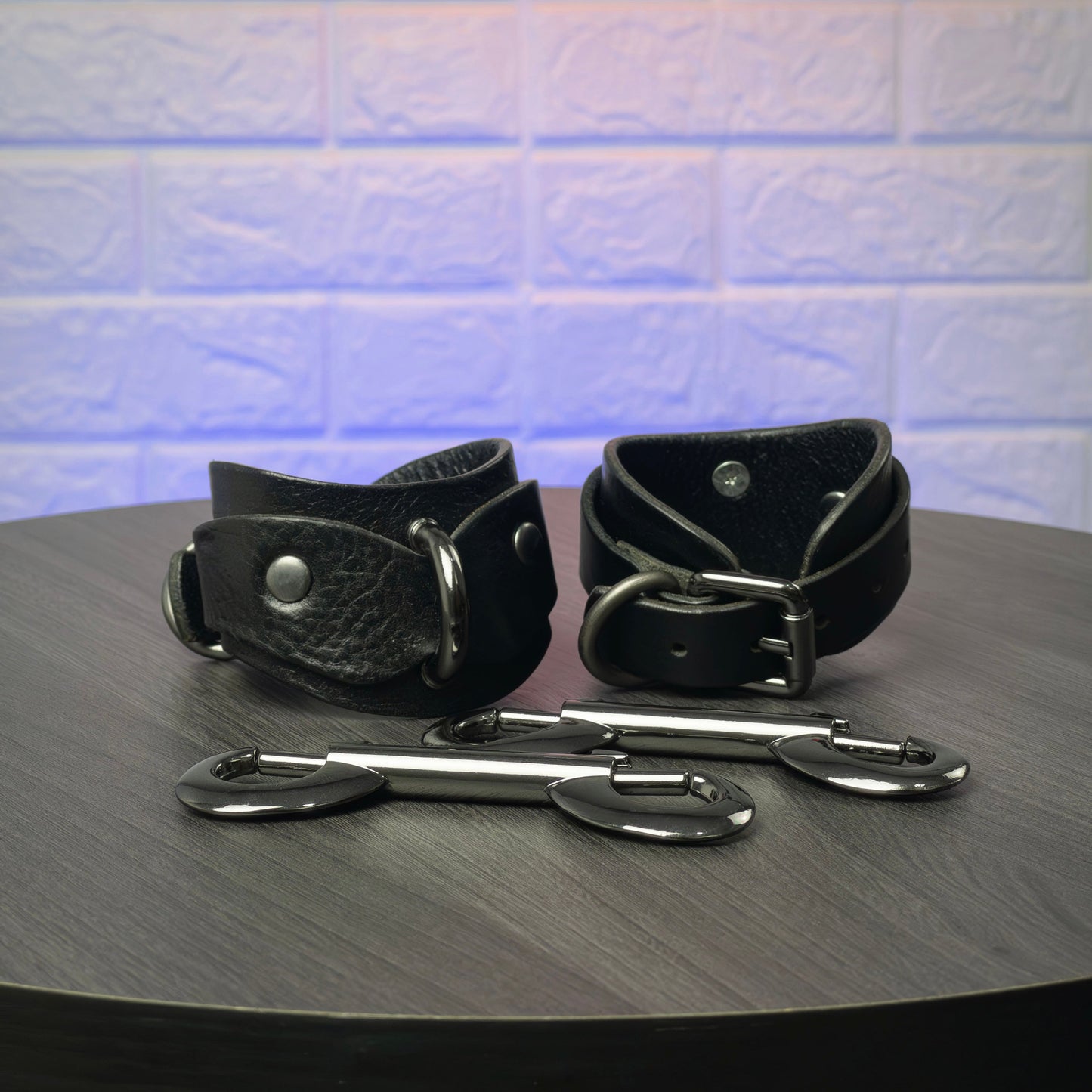 Black leather cuffs with metal hardware on a wooden surface