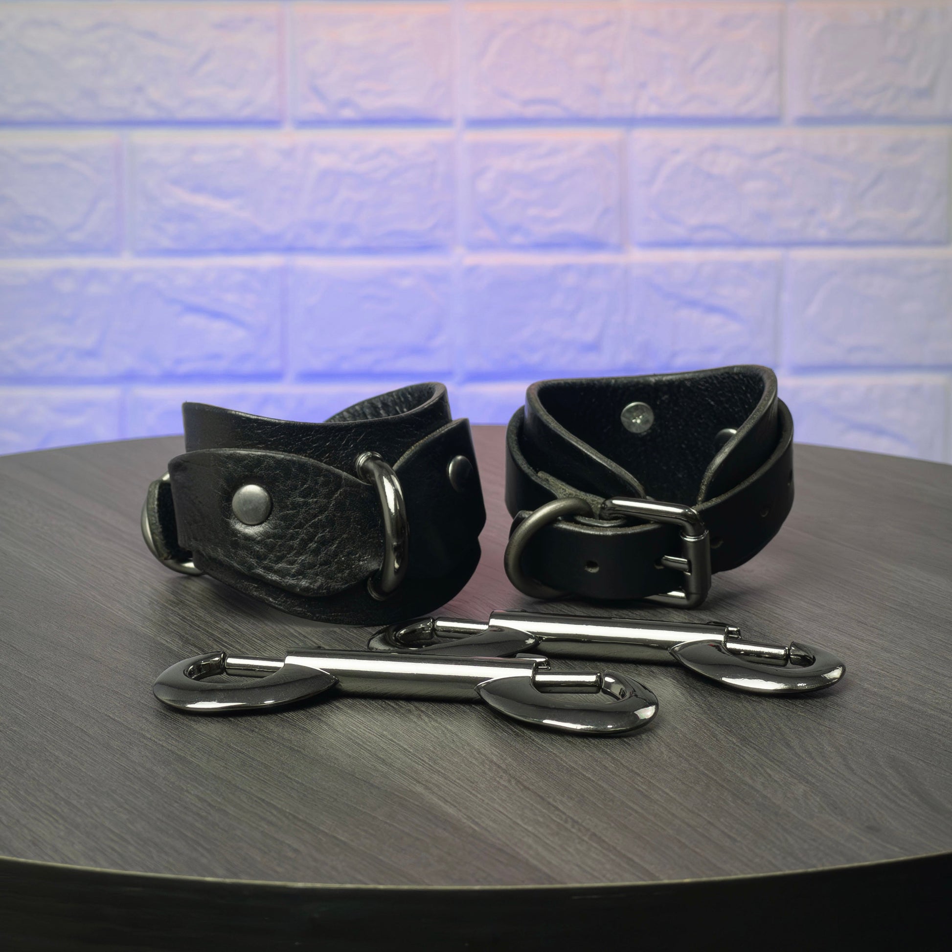 Black leather cuffs with metal hardware on a wooden surface