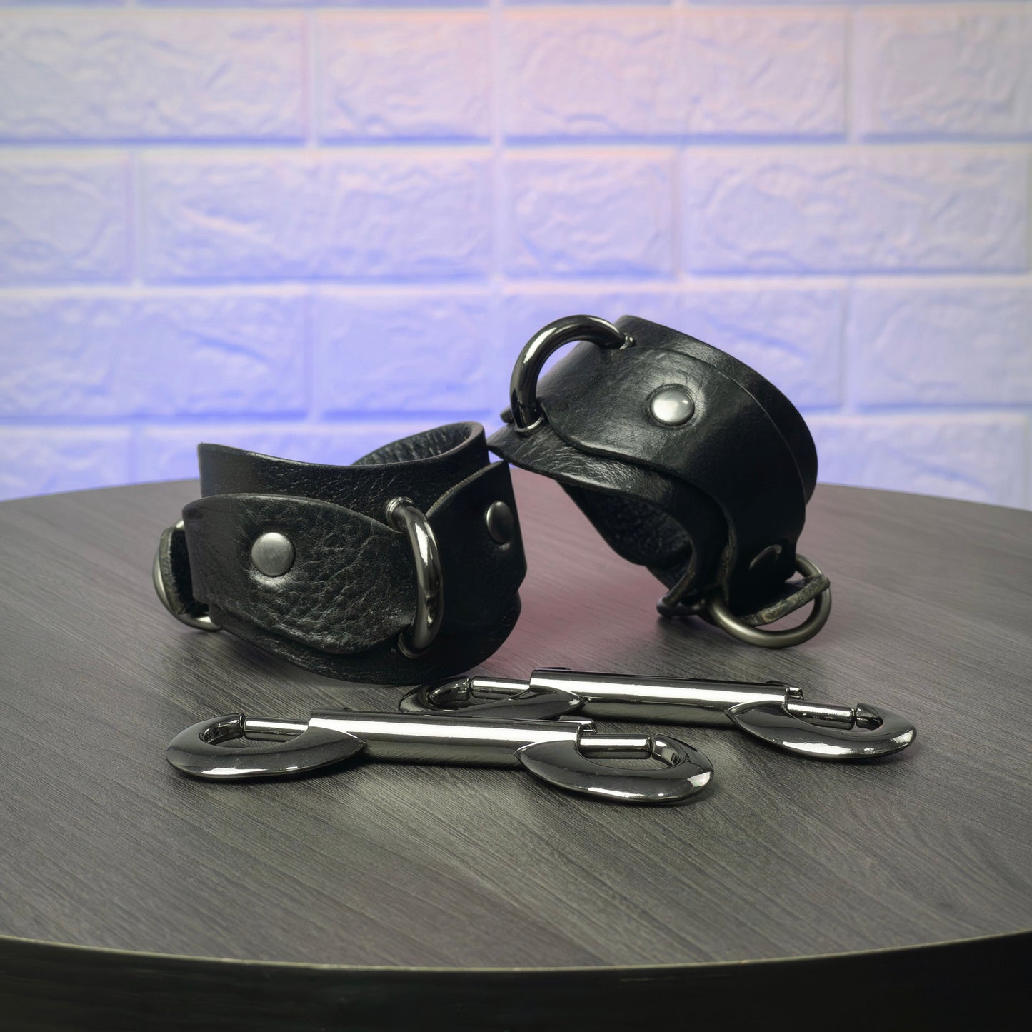 Black leather cuffs with metal clasps on a wooden surface