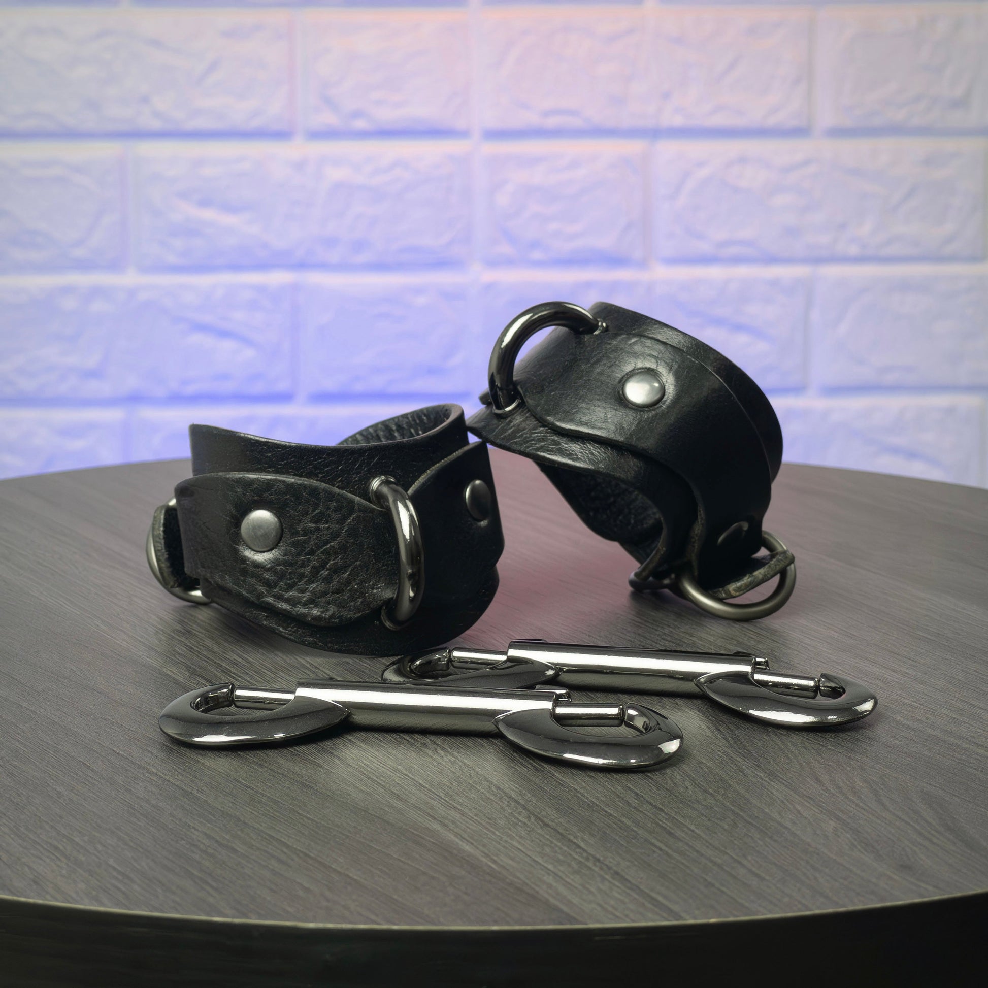 Black leather cuffs with metal clasps on a wooden surface
