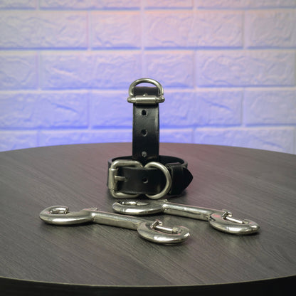 Black leather handcuffs with silver hardware on a wooden surface