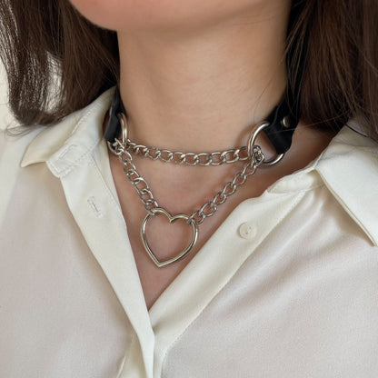 Black leather choker with silver chain and heart ring, side close-up on neck