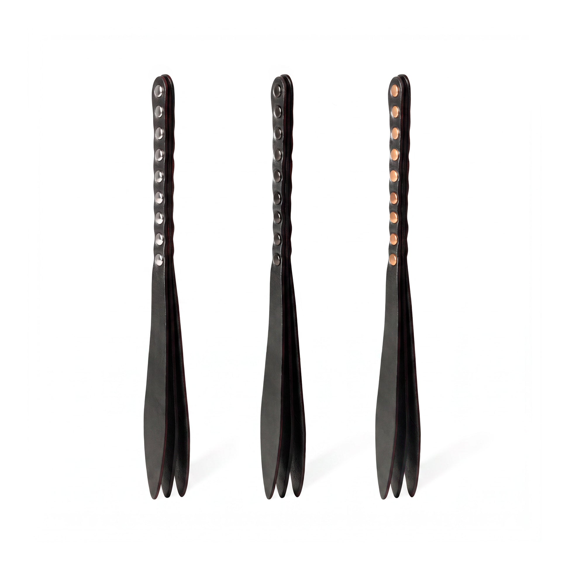 Three black leather bdsm paddles with hardware in silver, gold and dark nickel colors.