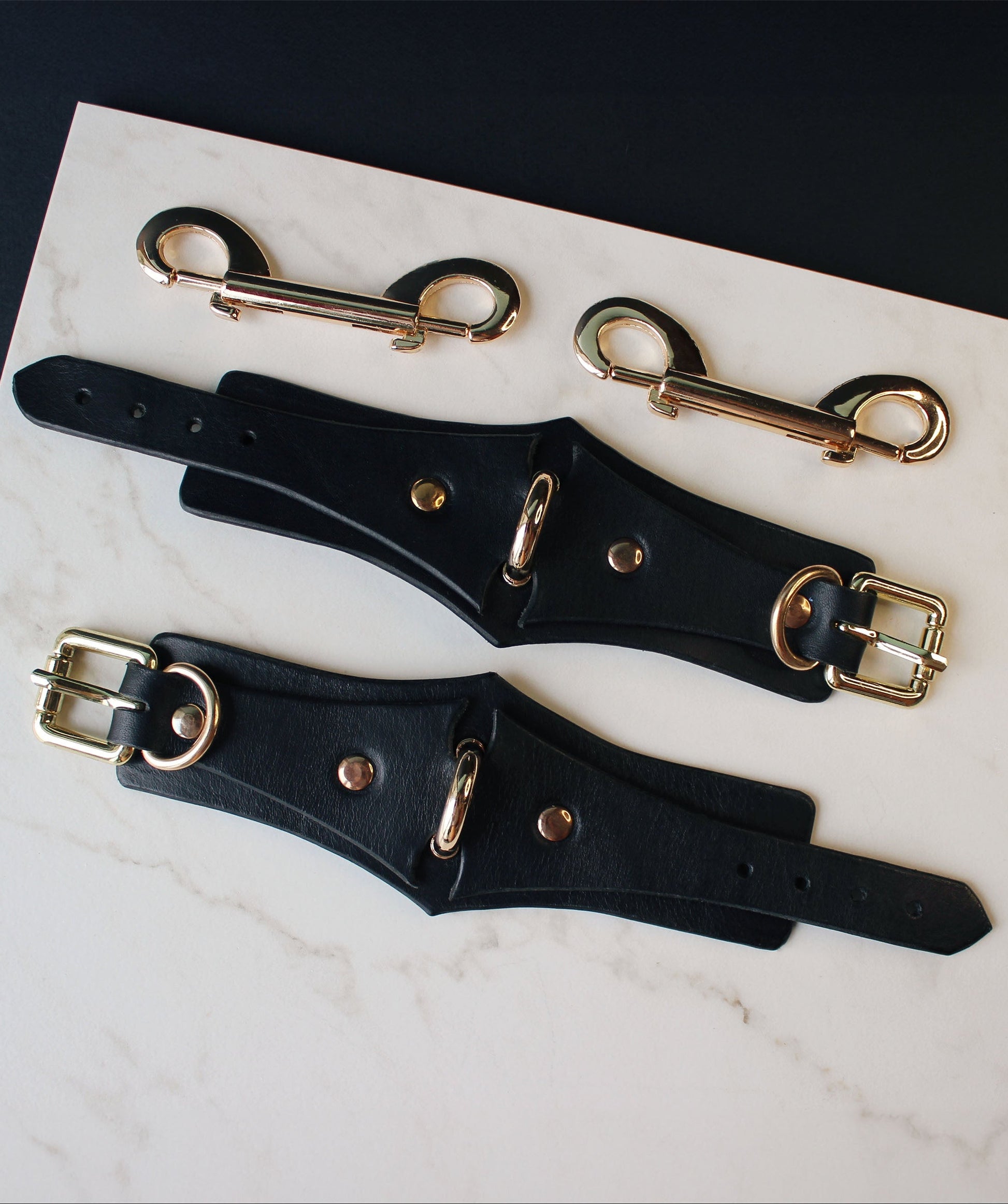 Black leather hardware with gold hardware on a marble surface