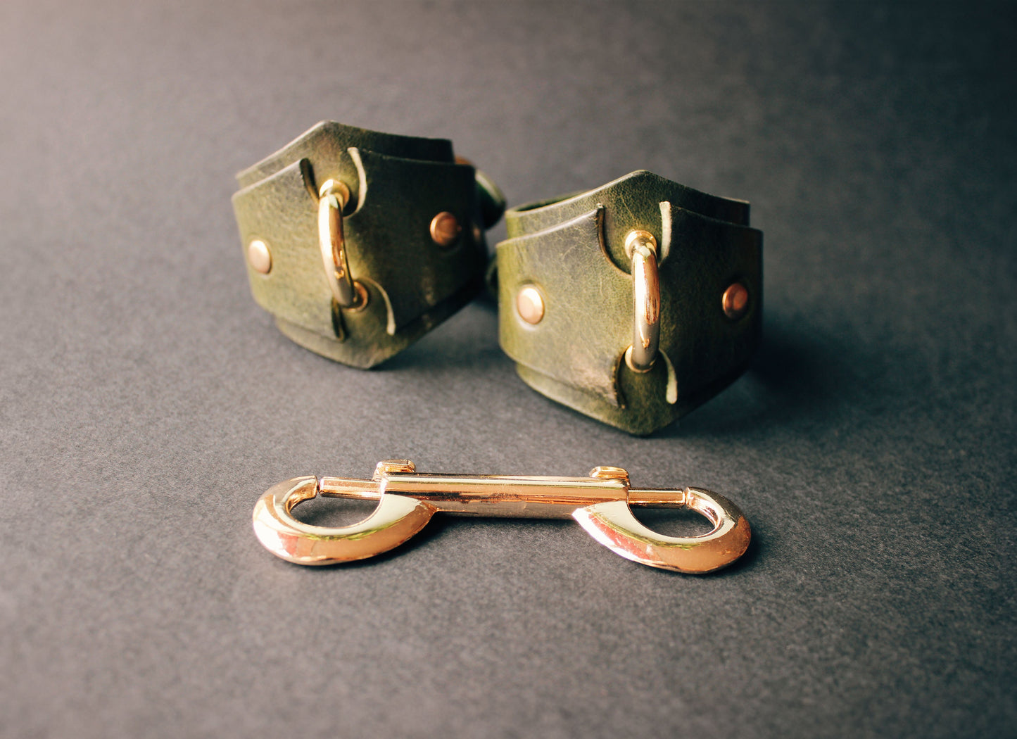 Pair of green handcuffs on a dark gray background