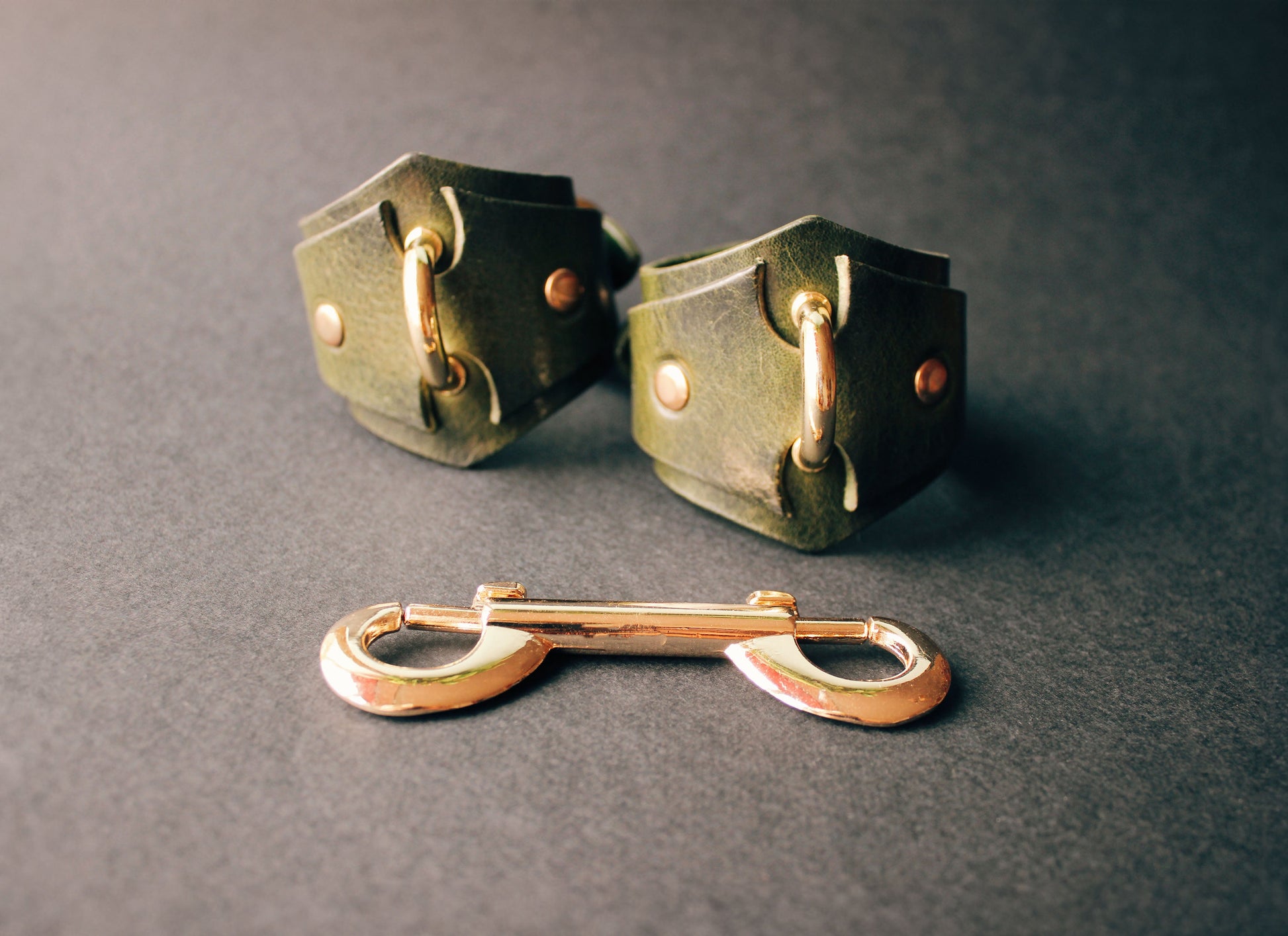 Pair of green handcuffs on a dark gray background