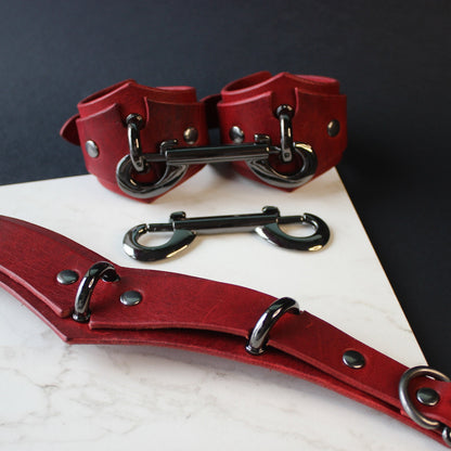 Red leather collar and cuffs set on a dark surface