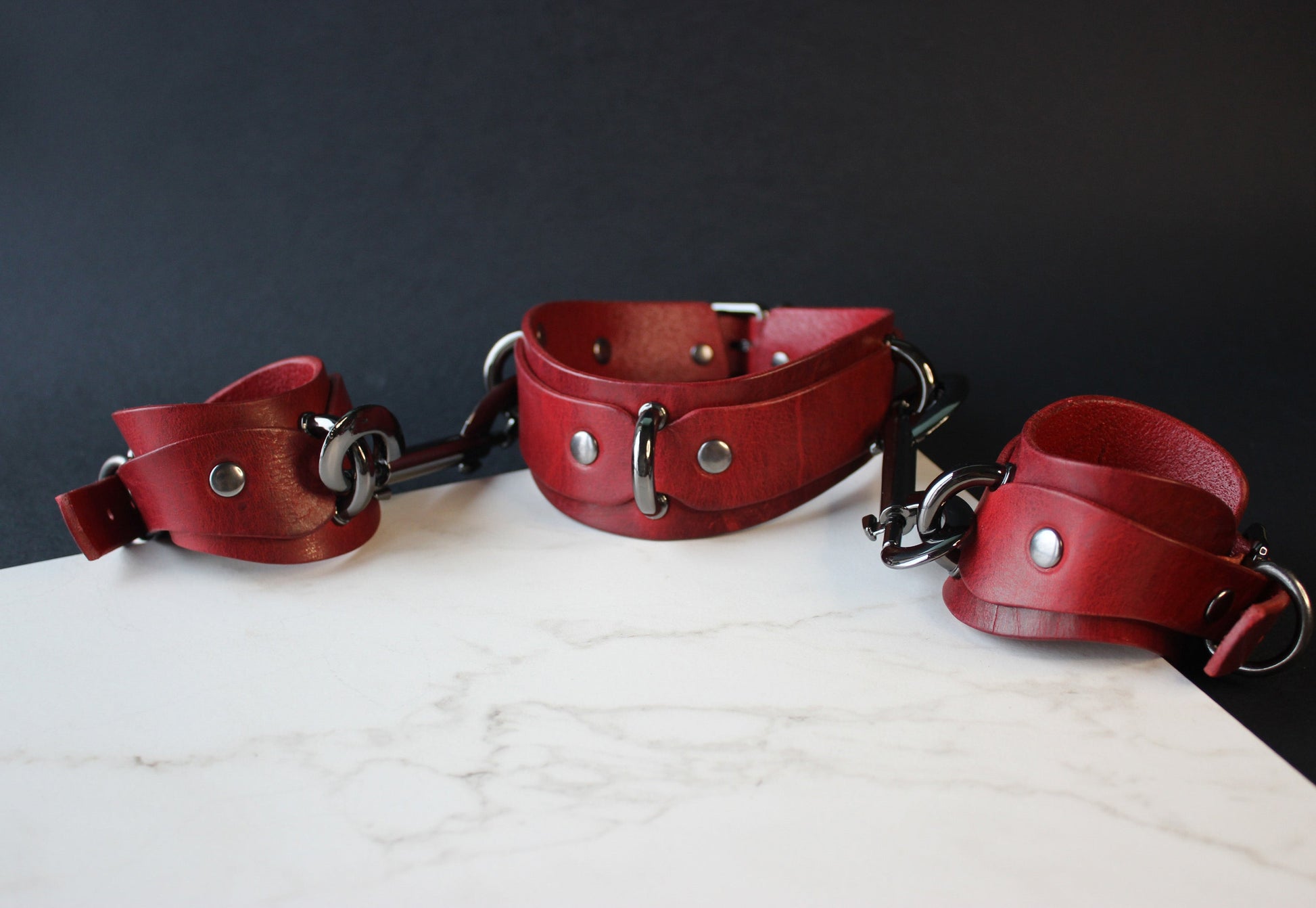 Red leather collar and cuffs on a dark background