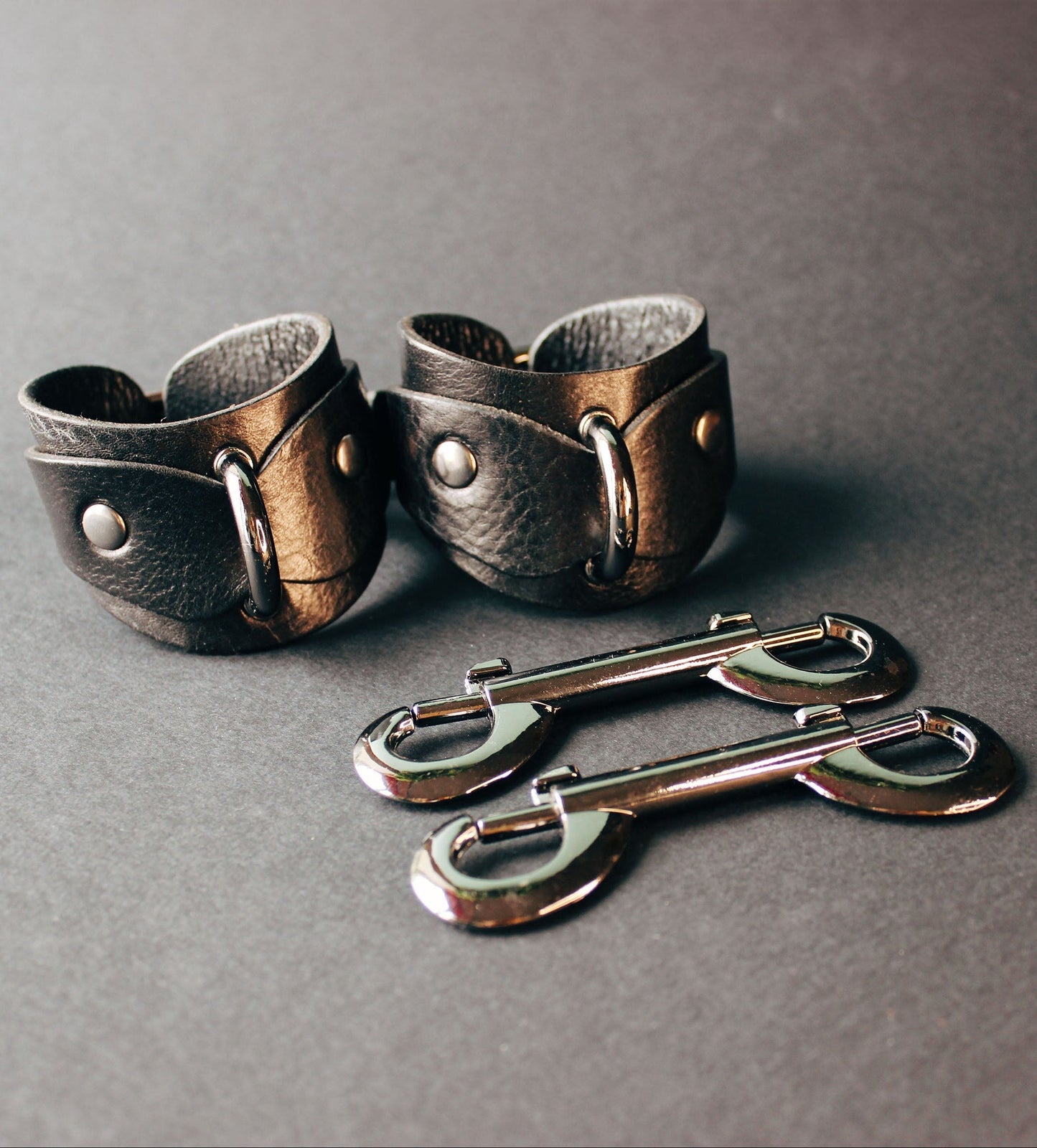 Pair of leather cuffs on a dark gray background