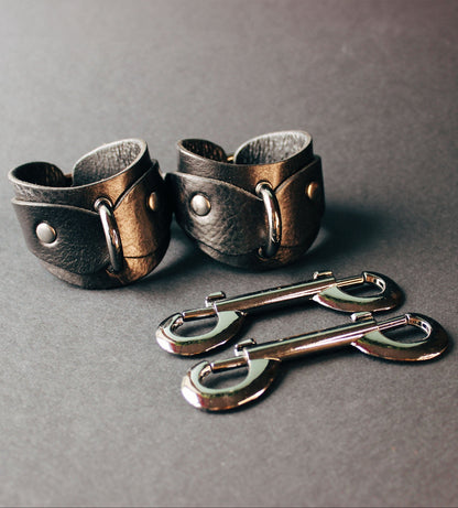 Pair of leather cuffs on a dark gray background