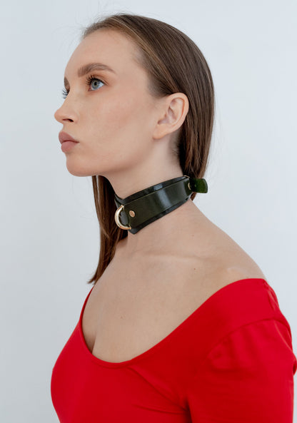 Woman wearing a green choker necklace against a white background