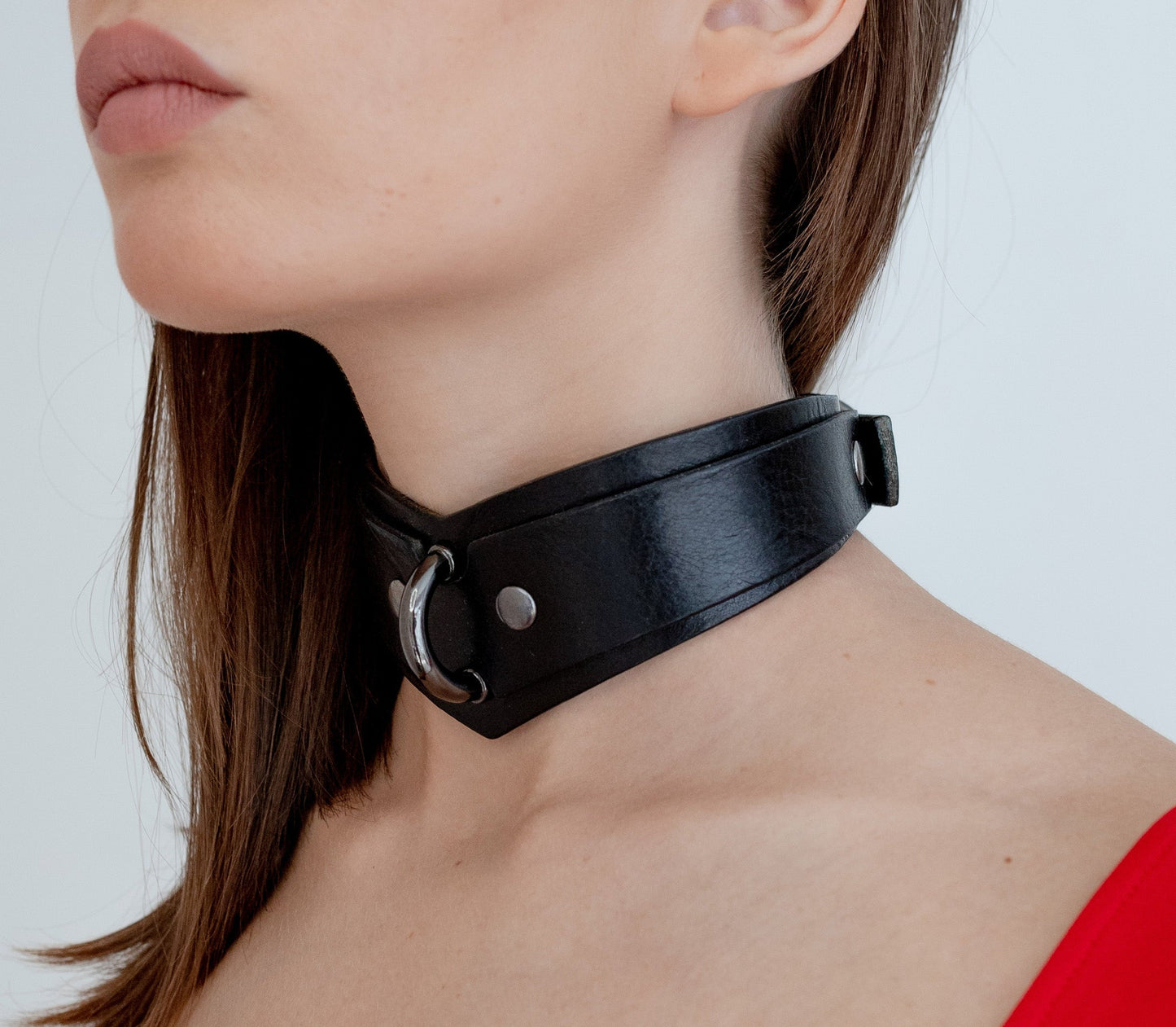Black leather choker worn by a person on a white background
