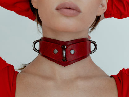 Close-up of a person wearing a red leather choker against a light background