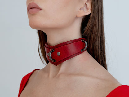 Red leather choker worn by a person against a white background