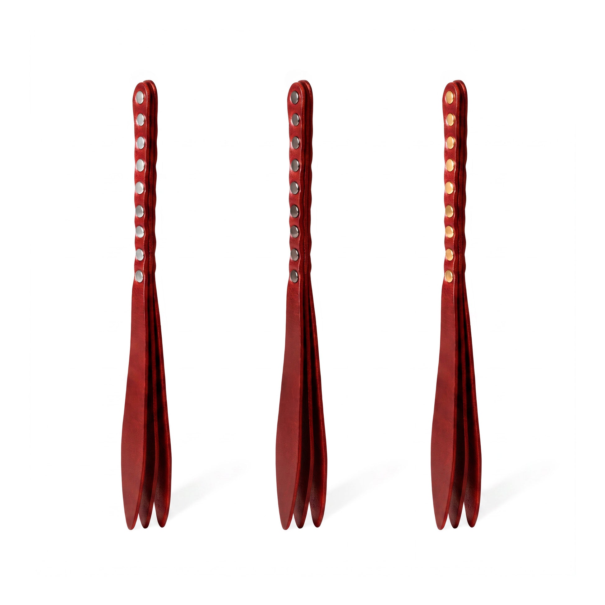 Three red leather bdsm paddles with hardware in silver, gold and dark nickel colors.