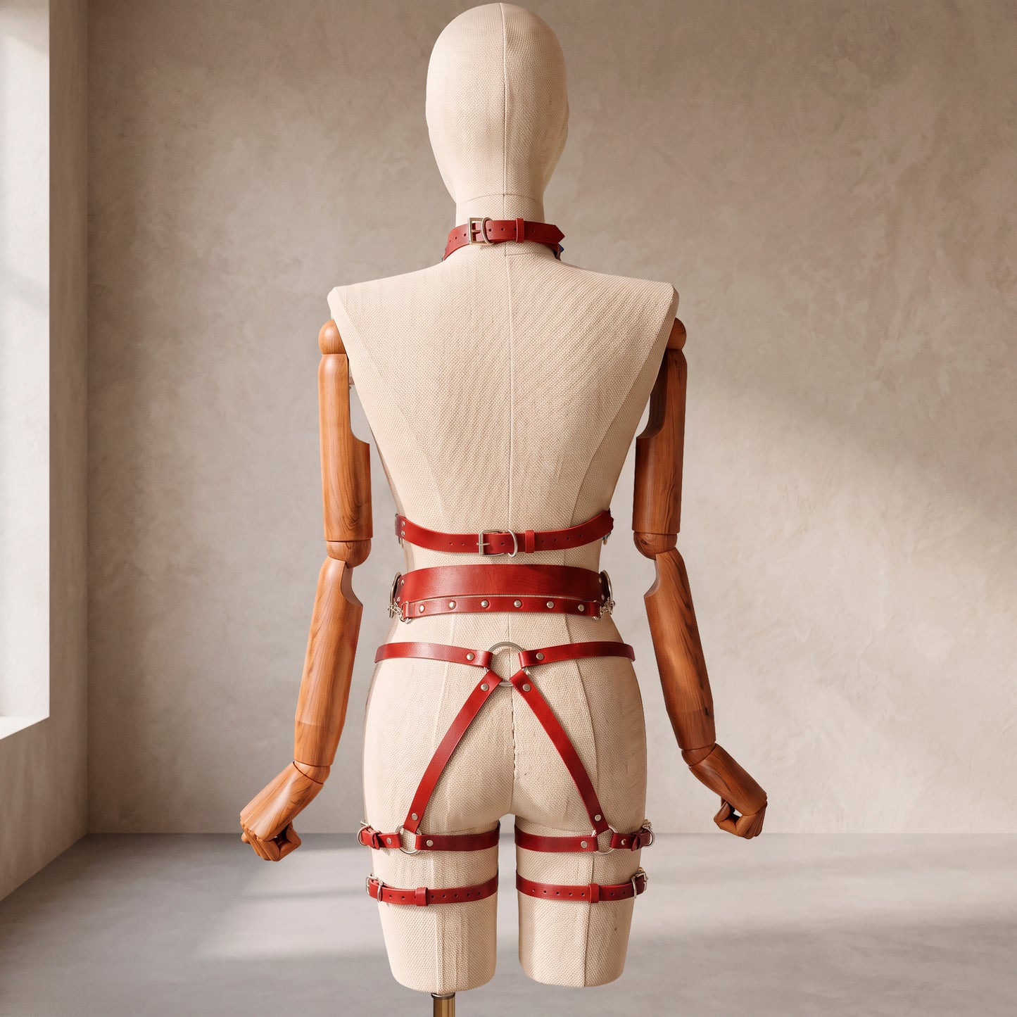 Back view of a deep red leather full body harness set with an open bust harness, open crotch garter belt, removable leather handle, large front ring, adjustable straps, and gold-tone metal hardware.